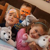 Two boys with homemade masks and a girl at be my bear party cuddling their bears