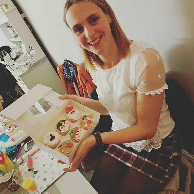 Lady holding white box of assorted christmas themed decorated cupcakes at adult workshop