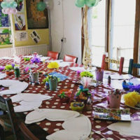 Craft party table set up to make butterfly decorations on red and white spotted tablecloth