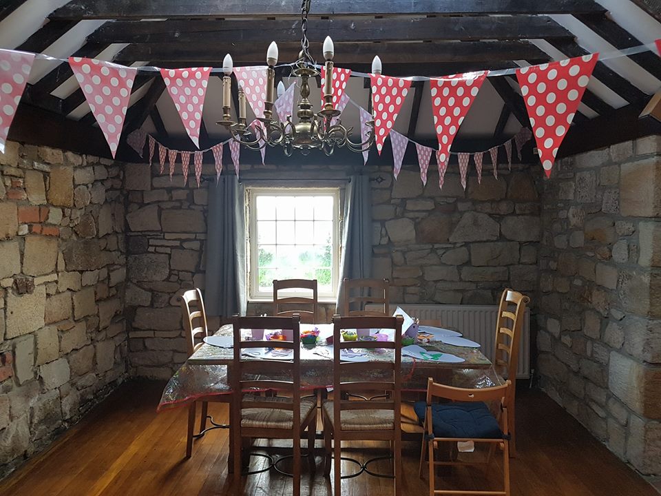 Party room set up with table, crafts and red and white spotted bunting