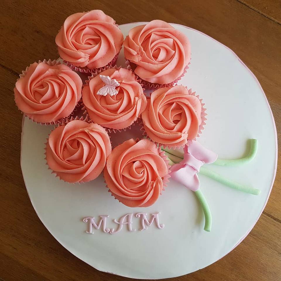 7 pink rose cupcakes on white board in bouquet arrangement and the word "MAM"