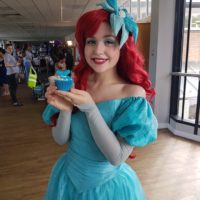 Woman dressed as Ariel from the Little Mermaid with decorated cupcake at childrens party