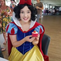 Woman dressed as Snow White with decorated cupcake at childrens party