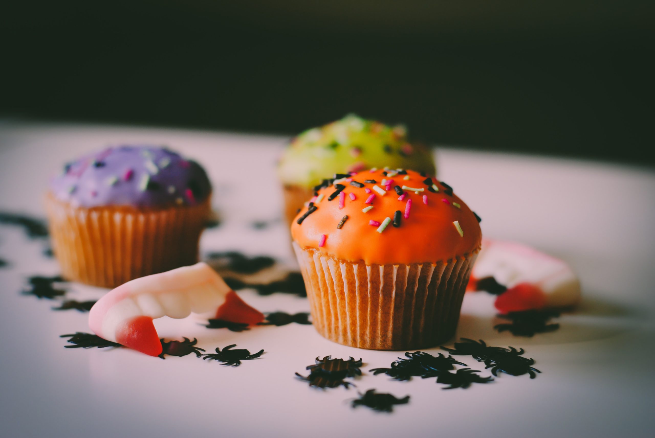 Halloween party cupcakes on a table with spider confetti and fang sweets