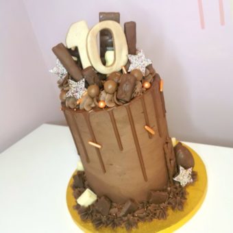 Tall chocolate buttercream 10th birthday drip cake decorated with assorted chocolates