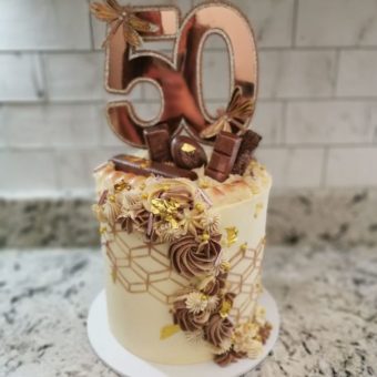 Tall buttercream cream, brown and gold art deco patterned 50th birthday cake