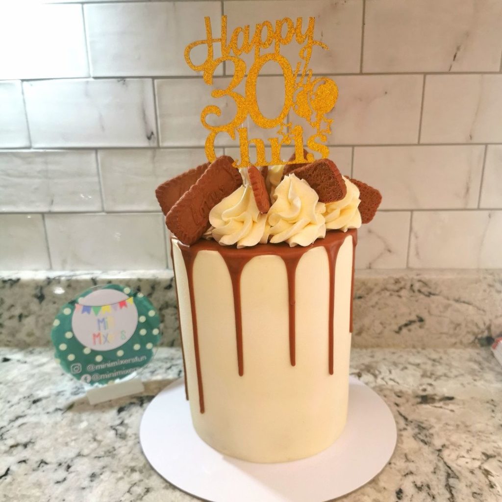 Tall white chocolate buttercream 30th birthday drip cake decorated with cream swirls and biscoff
