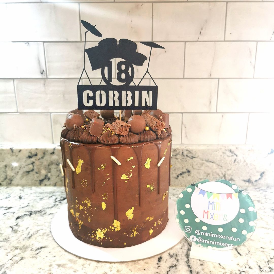 Chocolate drip and gold 18th birthday cake decorated with assorted chocolates and "18 Corbin" drum topper