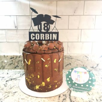 Tall chocolate drip buttercream 18th birthday cake decorated with assorted chocolate and a black "18 Corbin" drum kit topper