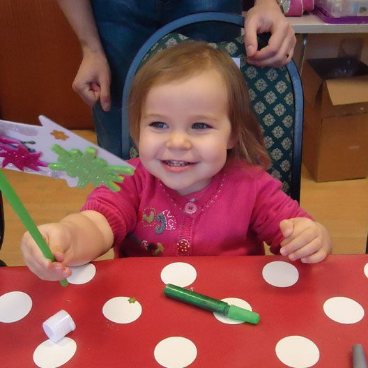 Girl at preschool craft session holding the craft she has made