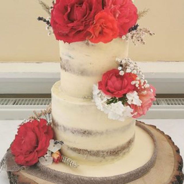 Two tier cream and silver buttercream wedding cake decorated with red, pink and white flowers